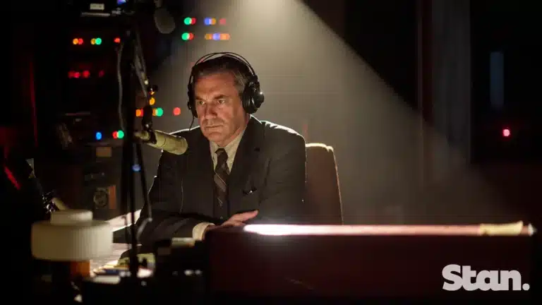 Jon Hamm as radio reporter Fred Heckman at a microphone in American Hostage