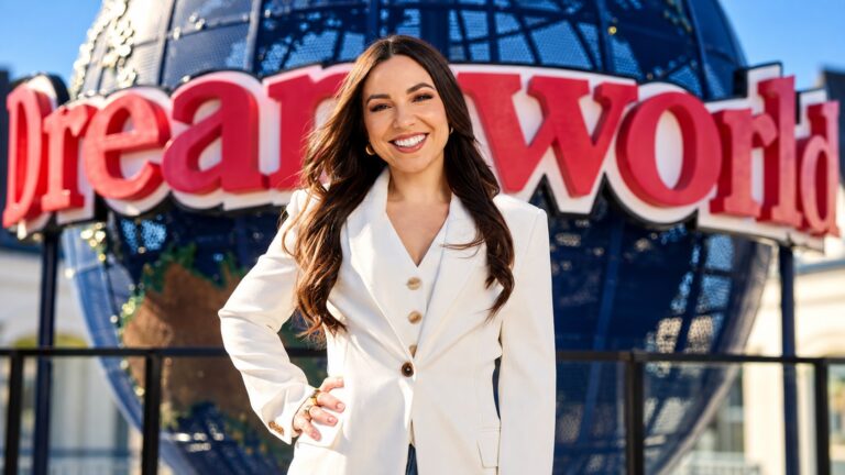 Big Brother host Mel Tracina in front of Dreamworld’s globe and sign