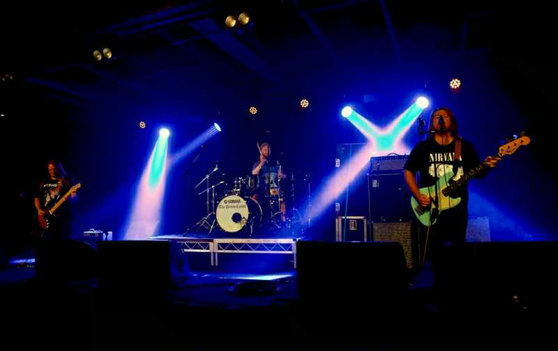 Rainbow Skull Party performing as a three-piece under blue and purple stage lights
