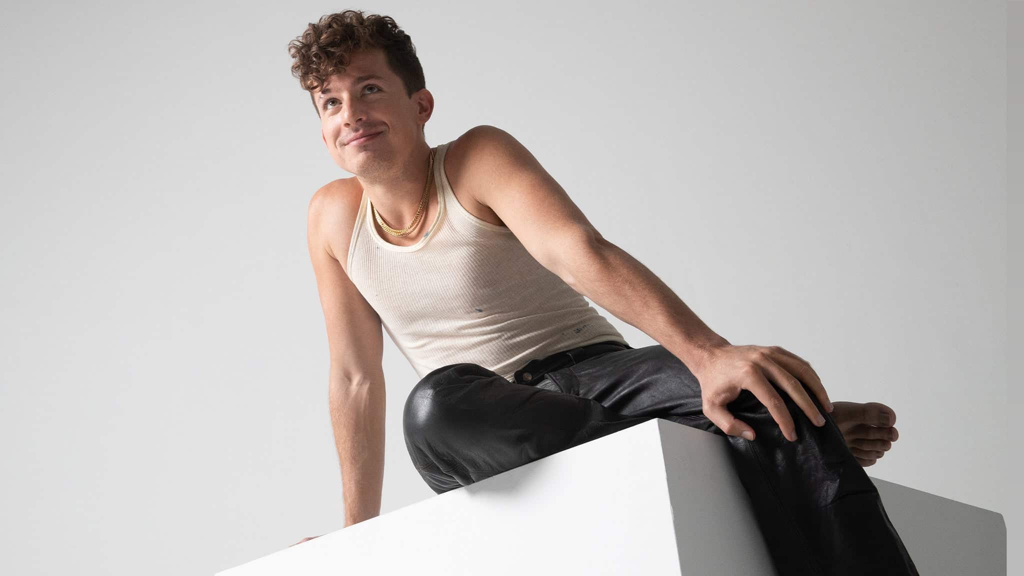 Charlie Puth seated in a white studio portrait for his 2026 tour
