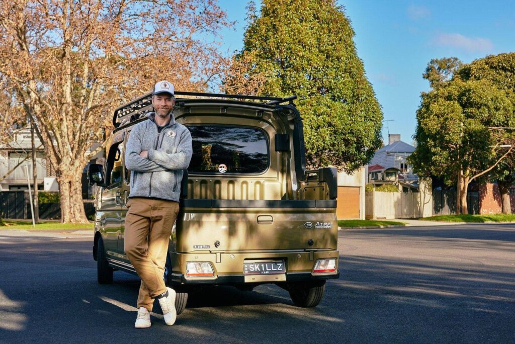 Hamish Blake leaning against the Unskilled Adult work truck