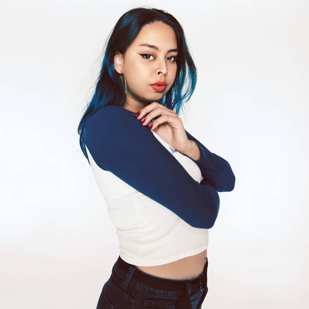 Grace Chia with blue hair and a navy-and-white top against a white background