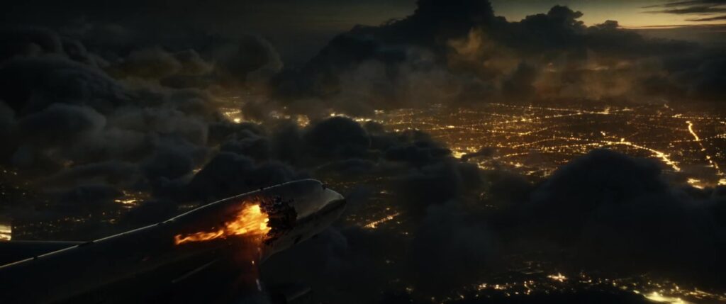 A burning passenger plane descends towards city lights in the Joseph music video
