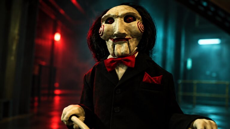 Billy the puppet from Saw in a red and teal industrial corridor