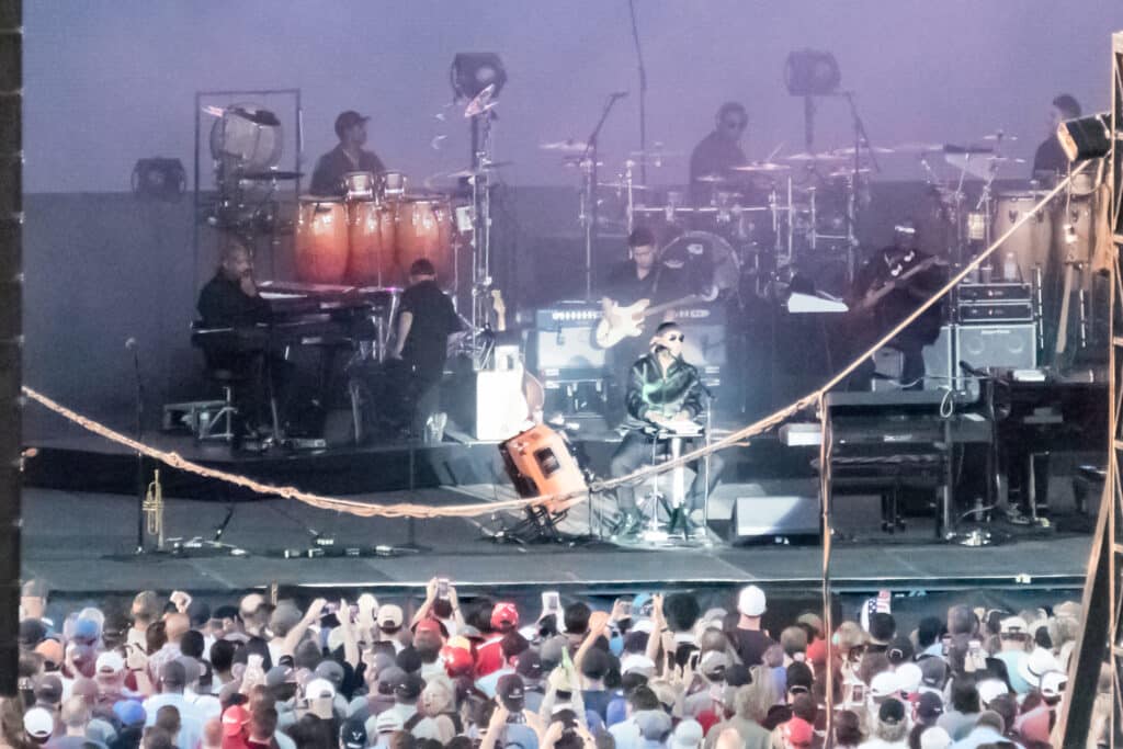 Stevie Wonder performing at a keyboard before a large concert crowd