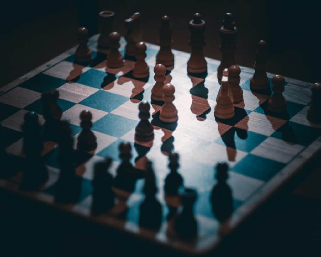 Wooden chess pieces on a board in dim light, illustrating the shifting strategy of The Traitors Australia