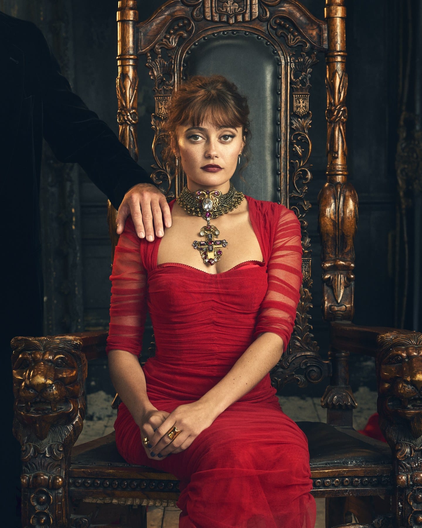Ella Purnell as Mina in a red dress seated on an ornate chair