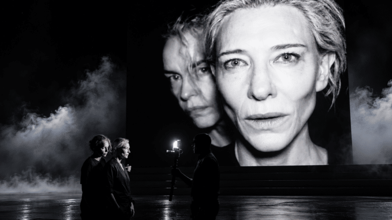 Cate Blanchett projected above performers on the dark Electra Persona stage