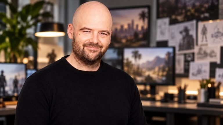 Dan Houser seated in a game studio with screens behind him
