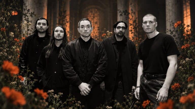 Deafheaven standing together in monochrome among muted orange poppies