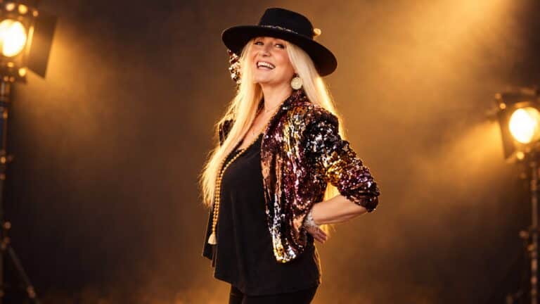 Canadian rock singer Sass Jordan smiling in a sequined jacket and black hat