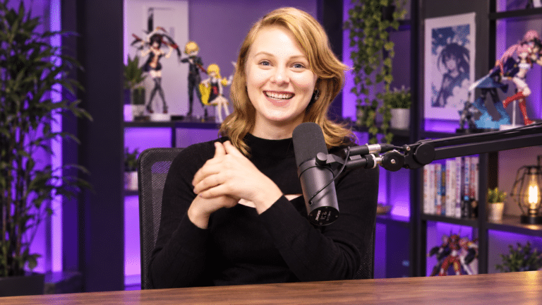 Sydsnap smiling at a podcast microphone in a purple-lit studio.