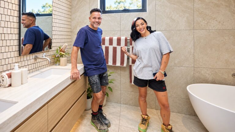 Rick and Tayla stand together in a pale blue tiled bathroom