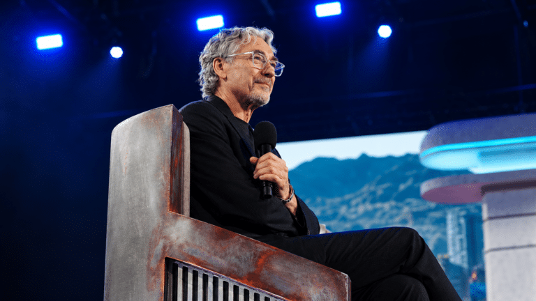 Tony Gilroy speaking onstage under blue lights