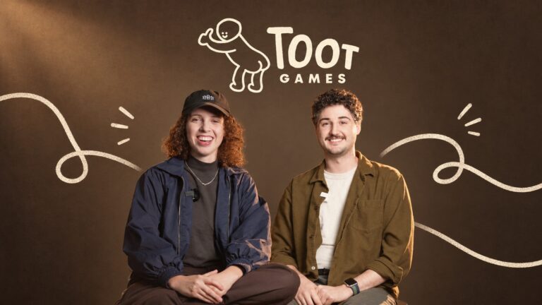 Toot Games co-founders Millie Holten and Matthew Jackson beneath the studio logo