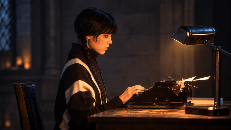 Jenna Ortega as Wednesday Addams typing at a desk after Wednesday Season 3 wrapped production