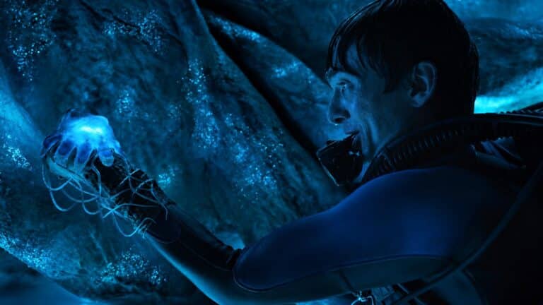 Austin Abrams as Jay Gardiner studies a glowing object inside the blue organic interior of a sperm whale in Whalefall